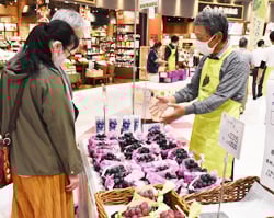 買い物客にブドウの特徴を説明する生産者（右）