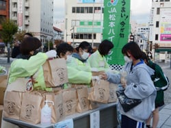 農産物の詰め合わせを配布するメンバー