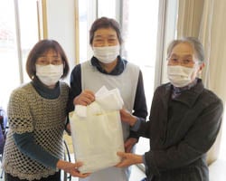 管理者の荒川さん（中央）にタオルを手渡す「ポケットの会」会長の丸山さん（右）と副会長の大塩さん