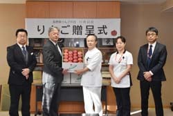 リンゴを宮下院長(＝左から3番目)に贈呈する神農組合長(右から2番目)