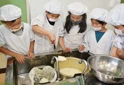 出来上がった豆腐を丁寧にざるに移す児童