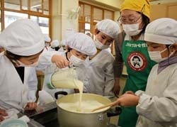 豆腐作りに励む児童（左）と女性部員（右）