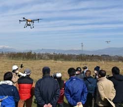 ドローンをホバリングさせ性能等の説明をする担当者（左）から2人目