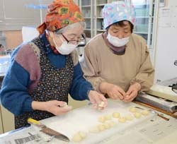 新村講師（左）に教わりながらものぐさ太郎まんじゅうを作る参加者
