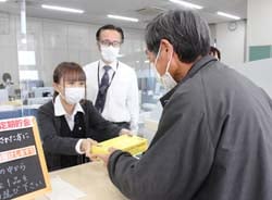 来店者に注意喚起のボックスティッシュを手渡すJA職員