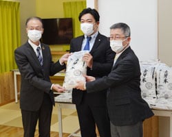 米を渡す白鳥常務（左）と受け取る宮下会長（右）、藤城村長
