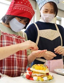 ホットケーキを重ねてクリスマスケーキをつくる参加者