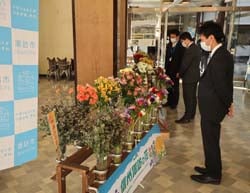 諏訪市制80周年式典の会場に飾られた管内産花きを眺める人たち