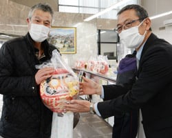 本沢理事から福だるまを受け取る組合員（左）
