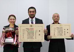 賞状を手に笑顔のゲインズさん（中央）ら