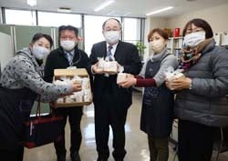 矢島教育長（中）に廃油石鹸を手渡し、子どもたちに配布してもらうよう伝えた寄贈式