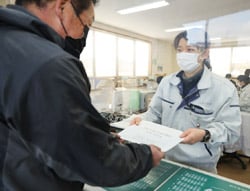 生産者に水稲栽培の学習資料を配布する職員
