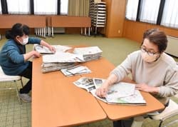 新聞袋を作る女性部役員2人