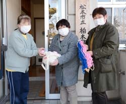 先生（左）にお手玉とあやとり紐を手渡す女性部員