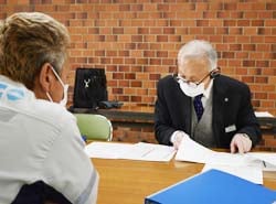 参加者（左）の書類に目を通す税理士（右）