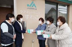 ケアネットセンターすわこの職員に介護用手袋を手渡す女性部3役