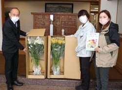花を手渡すJA職員（右）と受け取る両澤校長（左）