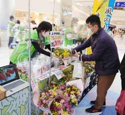 来店者にアルストロメリアと米を販売する山本支所長