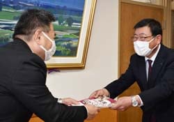 小松校長（左）に教材を手渡す丸山常務（右）