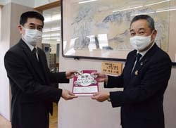浦山校長へ冊子を手渡す鳥原部長（右）