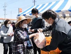 柑橘類を受け取る来場者（左）とJA職員（右）