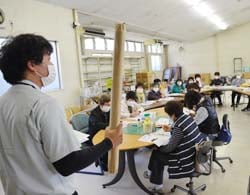 資材を見せて話す倉澤指導員と耳を傾ける参加者