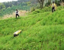 急傾斜の畦畔で草を刈るラジコン機