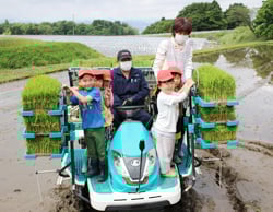 皆に見守られながら田植え機に乗る園児たち