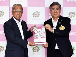 補助教材を手にする峯村教育長（右）と眞島組合長