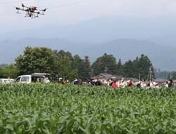 ドローンによる散布の様子を見学する参加者