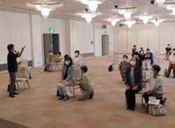 講師の説明に合わせて体操をする参加者