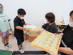 女性部役員からレタス蒸しパンを受け取る洗馬小学校の児童