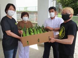 中村委員長と寺澤専務からトウモロコシを受け取る妙義保育園の先生