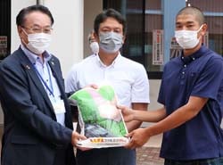 農畜産物を手渡す高栁副組合長（左）と藤原監督、寺尾キャプテン