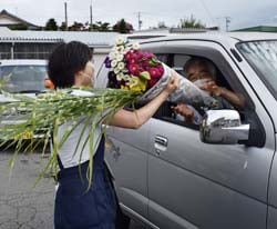 ドライブスルー形式で盆花を受け取る来場者