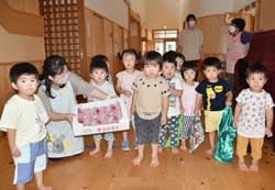 JAから贈呈したトマトを持つ野口園長と園内の子どもたち