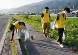 道路わきや河岸のごみを拾い集めるJA職員