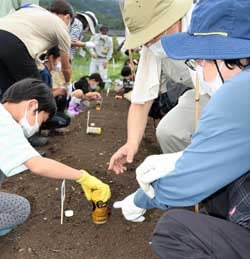 空き缶を使って種まきの穴を作る児童（9月3日、上田市下之条）