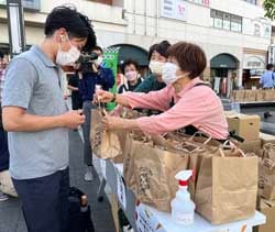 農産物の詰め合わせを配付するメンバー