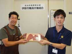 肉を手渡すJA職員と受け取る労組員