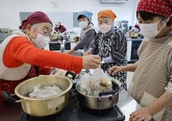 耐熱用ポリ袋に食材などを入れ、湯せんする大学生