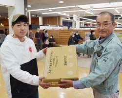 JA商品を渡す大場理事（手前）と受け取る来場者