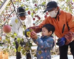 園主の田島さん(右)から収穫のコツを教わる子