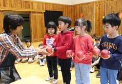 園児にリンゴを手渡す塩原理事