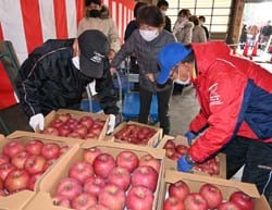 自家用リンゴを品定めする来場者（中央）とJA理事（右）