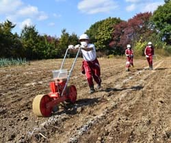 播種機を使って楽しく種まきをする児童ら