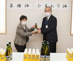 油を寄贈する細萱代表とセンター長ら