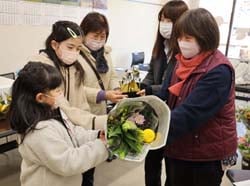 孫と一緒に受取りに来た参加者に花材を手渡す部員（右）