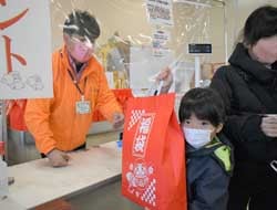 福袋を渡す後藤店長（左）と受け取る来場者（右）