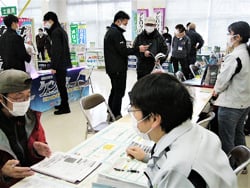 賑わう会場で相談を受けるJA職員